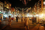 picture taken in evening, having a bazaar with people walking around, and food shops.