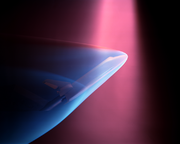 A violet beam from above produces a blue glow about a Space shuttle model