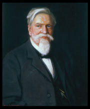 A color portrait of an older gentleman with white hair and a white goatee