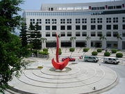 A white medium-rise building with a red sundial in the courtyard.