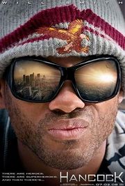 Close portrait of a man with stubble on his face and large sunglasses in which the reflection of a city's landscape, awash in sunlight, can be seen.  The man is wearing a gray knitted cap with a dark red rim; stitched in the front of the cap is a orange-tinted bald eagle with its wings spread.  In the lower right corner of the poster is the name "HANCOCK".