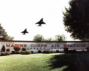 color photo fo a pair of Harriers in flight over the lanscaped sign reading "Marine Corps Air Station Cherry Point"