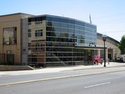 The main fire station is two stories tall with beige colored brick on the exterior. On the front is a atrium spanning both levels built with tinted glass.