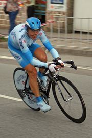 A cyclist in a two-tone blue skinsuit, wearing an aerodynamic helmet with a visor..