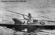 "black and white image of an [Inuit hunter seated in a kayak holding a harpoon"