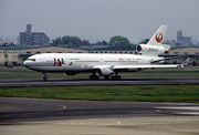 A three-engine aircraft on an airport runway, facing left.