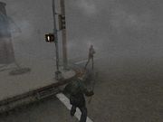 A screenshot from a video game. On a the corner of a foggy street, a monster with no arms faces a man in a green jacket wielding a pipe.