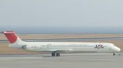 A McDonnell Douglas MD-81 aircraft  taxiing on the tarmac, with a grey looking seaview on the background