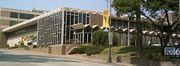  A large tv station building. The building has many windows and a large awning runs parallel to one side. A small sign out front and a large sign on the side of the building both say KWQC TV 6