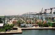 Harbor dock, with many rows of containers, and large cranes for loading on to ships.  The cranes are labeled 'Evergreen.'