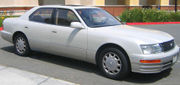 Angled side profile of sedan parked in front of a building.