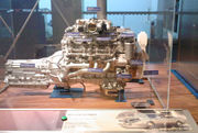 Side view of a V8 engine and transmission, with exposed components and identification labels attached.