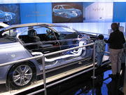 Cutaway hybrid car showing electrical connections; auto show display backdrop.