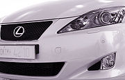 Car front fascia, partial view, with trapezoid grille, right headlight, and bumper.