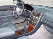 Automobile front interior, passenger side, showing dashboard, wood center console, and leather trim.