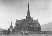 A timber framed, wooden church with  plank walls and tiered roof, steeply pitched. It has a tall, slender spire and few windows.