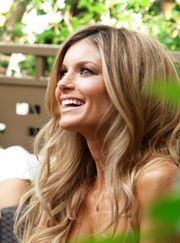 Blonde woman smiling while sitting in a public lounge.