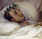 Gold-framed portrait painting of a gaunt middle-aged man with receding hair and laurel wreath, lying eyes-closed on white pillow with a white blanket covering to his neck and a gold Jesus cross resting on his chest