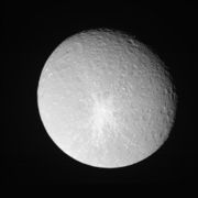 A spherical body is almost fully illuminated. Its grayish surface is covered by numerous circular craters. The terminator is located near the upper-right limb. A large crater can be seen near the limb in the upper-left part of the body. Another smaller bright crater can be seen in the center. It is surrounded by a large bright patch having the shape of a five-pointed star.