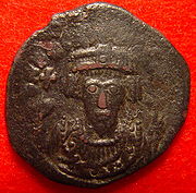 A silver coin with the bust of Phocas. His eyes form the central focus of the image