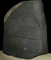 "A large, dark grey-coloured slab of stone with text that uses Ancient Egyptian hieroglyphs, demotic and Greek script in three separate horizontal registers"