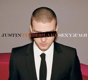 A young man with a buzz cut, wears a two-piece black suit, with a white shirt and black tie. A black horizontal rectangle covers his left eye, while his right blue eye can be seen. In capitals, "Justin", "Timberlake", and "SexyBack" is written in black, orange, and white font, respectively. The word "Back" is spelled backwards.