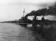 A large gray warship, heavily flooded, it's deck is nearly submerged. Thick black smoke pours from the funnels. An in-photo caption reads: "Seydlitz nach Skaggerak-schlacht", or "Seydlitz after the Skaggerack battle."