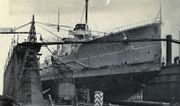 A large ship sits in a drydock, surrounded by construction equipment.