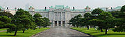 A  large palace built of white stone in neo-baroque style. The facade is adorned  with colons.