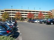 parking lot in foreground; a parking garage (four levels) in background