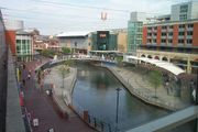 Stretch of canal with large modern buildings and concrete walkways on either side.