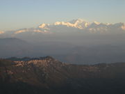 Snow-capped mountain peaks visible in the distance, with forested hills in the foreground.