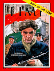 Time magazine cover depicting an armed male with unruly hair and a determined look on his face, wearing a blue coat, a green scarf and gloves with the fingertips cut out. A Hungarian flag with a circle cut out of its midddle is in the background