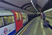 Side view of a tube train with red doors and an underground platform