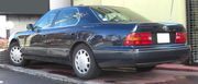 Rear quarter view of sedan parked outdoors next to a wall.