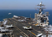 F/A-18 Hornet launches from the flight deck of Truman. Other aircraft are stored on deck.