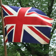 Union Flag flies on a flagpole with trees behind.