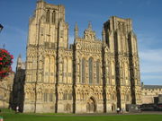 Yeloow stone building with buttressed towers on the left and right. Extensive decoration with statues.