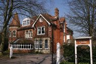 Red brick building partially obscured by trees.