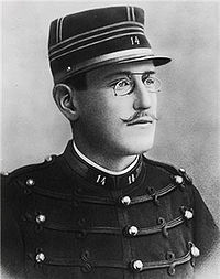 Head and torso of a young man wearing military uniform with spectacles and a moustache