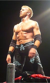 White male wearing black pants, black elbowpads, and no shirt.