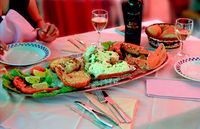 Photo of restaurant table holding a platter featuring unshelled lobster legs and claws