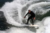 Photo of surfer wearing wetsuit catching wave