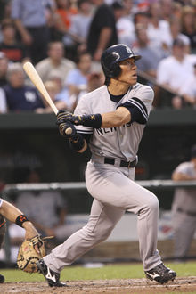 An asian male wearing a grey uniform with the lettering "NEW YORK" across it, in his after-swing pose.