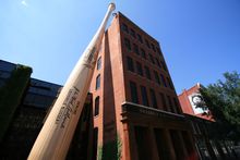 Large Louisville Slugger model bat stands up against the exterior of a brick museum building