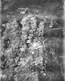 A photo taken from the air, plumes of smoke rise over a town.