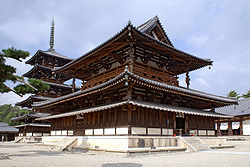 A  large wooden building with a hip-and-gable main roof and a secondary roof  giving the impression of a two-storied building. Between these roofs  there is an open railed veranda surrounding the building. Below the  secondary roof there is an attached pent roof. Behind the building there  is a five-storied  wooden pagoda with surrounding pent roof below the first roof.