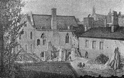 A monochrome illustration of several short buildings clustered in a small space.  A yard in the foreground is filled with detritus.