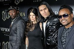 Two black men, a white man and a white woman standing in a line all wearing black clothing.