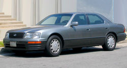 Angled side profile of sedan parked in front of a building.